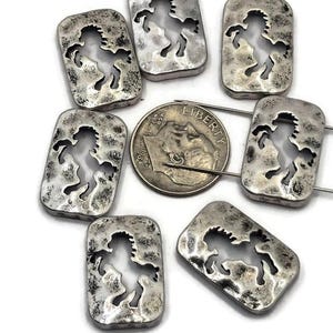 May include: Silver-toned rectangular beads with a cutout horse design. The beads have a hammered texture and are arranged around a dime. The horse silhouette is visible in each bead, creating a rustic, equestrian theme.