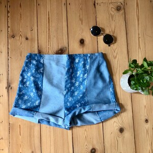 Peut inclure: Short en jean bleu avec un motif floral. Le short a une taille haute et est fait d'un patchwork de différents tissus en jean.