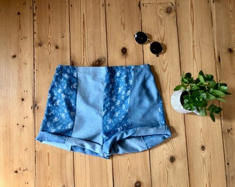 May include: Blue denim shorts with a floral pattern. The shorts have a high waist and are made of a patchwork of different denim fabrics.