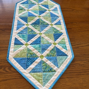 A springtime pop of color table runner.  Green and blue runner that is 13 by 31 inches long.  Machine quilted with decorative stitches.