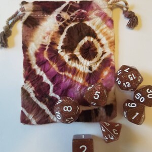 May include: A brown tie-dye drawstring bag with a set of brown dice with white numbers. The dice are a d4, d6, d8, d10, d12, and d20.