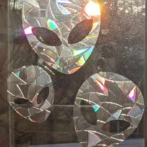 May include: Three iridescent alien head silhouettes made from recycled CD pieces. The alien heads are outlined in black and have a geometric pattern.