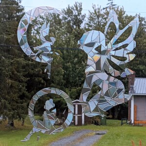 May include: A stained glass window sticker featuring a fairy with wings and a crescent moon. The sticker is iridescent and has a mosaic-like design.