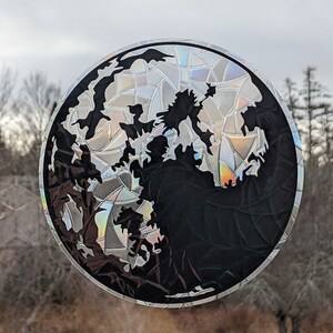 以下が含まれることがあります： 世界地図の黒いシルエットが描かれた、丸い虹色のステッカー。ステッカーはひび割れたガラスのような効果があり、窓やその他の滑らかな表面に貼るように設計されています。