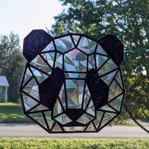May include: A geometric panda face sticker with a iridescent finish. The sticker is made of black vinyl with a holographic design.
