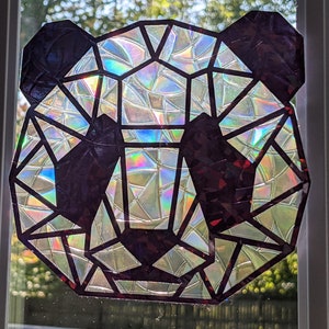 May include: A geometric panda bear design made of iridescent, holographic paper. The panda is outlined in black and the background is white.