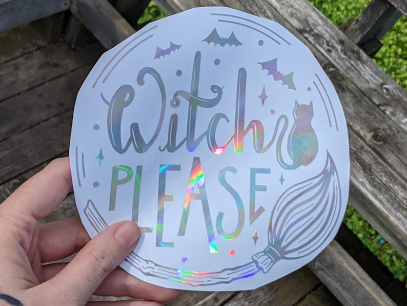 May include: A round, white holographic sticker with the words "Witch PLEASE" in a whimsical font. The sticker features illustrations of bats, stars, a cat, and a broom, all in a similar holographic finish. The design is perfect for Halloween.