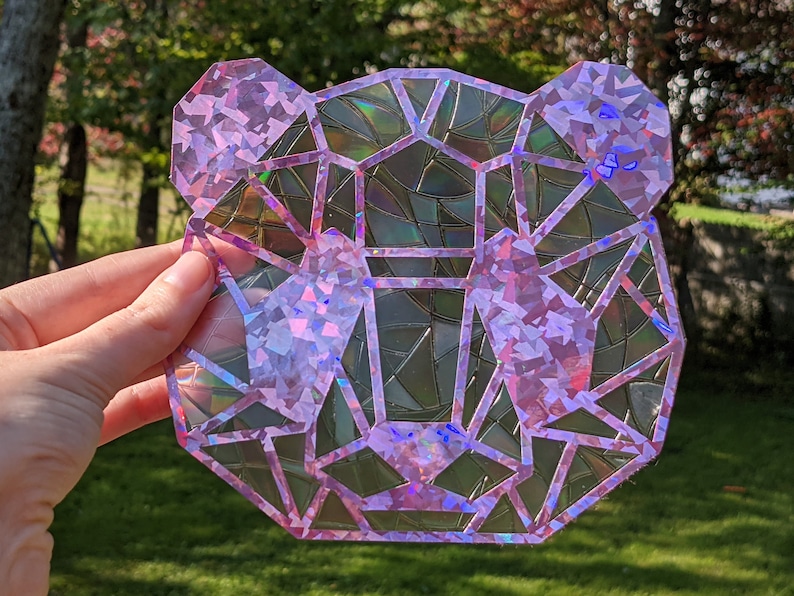 May include: A pink iridescent geometric bear-shaped sticker with a holographic finish.
