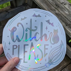 May include: A round, holographic sticker with the words "Witch Please" in a script font. The design includes bats, a cat, a broom, and stars. The sticker has a shiny, iridescent finish.