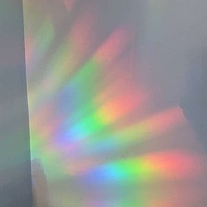 May include: A white wall with a rainbow prism light reflecting on it. The light is a spectrum of colors, including red, orange, yellow, green, blue, indigo, and violet.