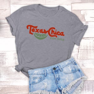 Puede incluir: Camiseta gris con el texto "Texas Chica con lima" en letras rojas y un gr&aacute;fico de una rodaja de lima verde.
