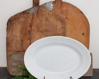 May include: Two rustic wooden bread boards with metal accents, leaning against each other, and a white oval serving platter on a black surface.
