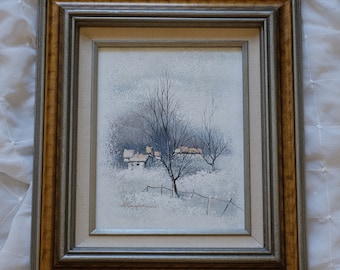 May include: A framed painting of a winter scene with a small village in the distance. The painting is done in muted tones of blue, white, and brown. The artist's signature is visible in the bottom right corner.