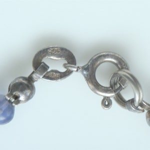 May include: A silver chain necklace with a silver clasp and blue gemstone beads.