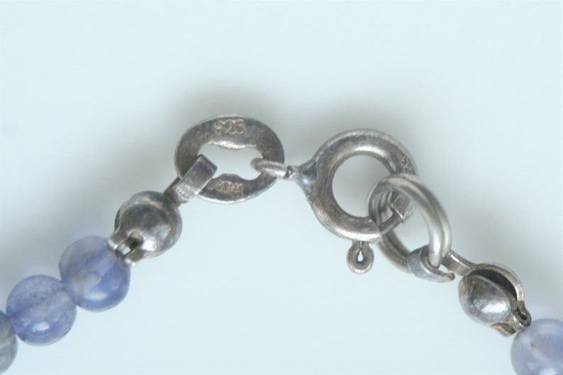 May include: A silver chain necklace with a silver clasp and blue gemstone beads.