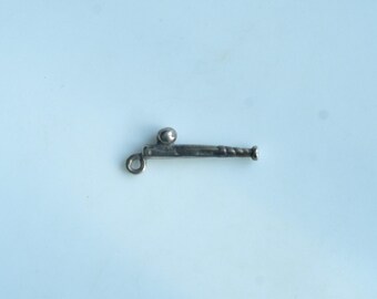 May include: A small, silver-toned cannon charm with a ring at one end and a ball on top. The cannon has a detailed barrel and is set against a light blue background. This charm is suitable for jewelry making.