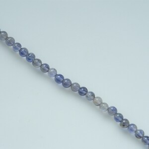 May include: A strand of round, light blue and gray gemstone beads.