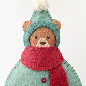 Felt ornament pattern. Felt christmas bear ornament. A felt brown bear wearing a red and green snowsuit. Felt bear ornament with pompom hat.