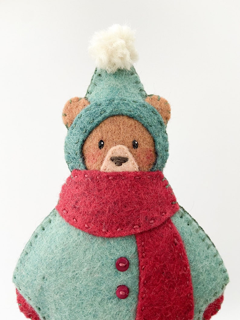 Felt ornament pattern. Felt christmas bear ornament. A felt brown bear wearing a red and green snowsuit. Felt bear ornament with pompom hat.