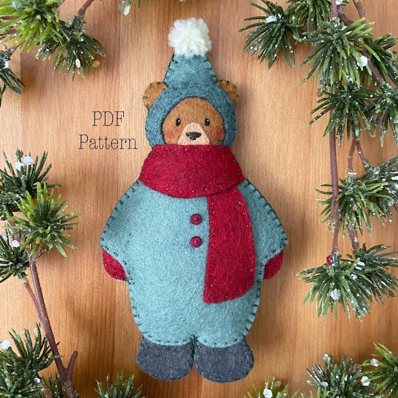 A felt christmas ornament bear dressed in a green snowsuit with red scarf. Text reads PDF pattern. Whimsical christmas ornament pattern. Felt ornament pattern. Christmas sewing pattern. Winter sewing project. Cute bear pattern.