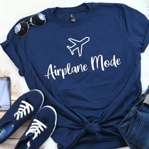 Op de afbeelding: Een marineblauw t-shirt met een witte vliegtuigafbeelding en de tekst "Airplane Mode" in wit.