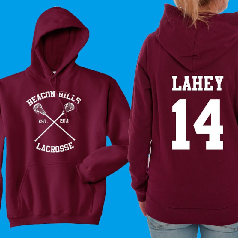 May include: A maroon hoodie with white text and graphics. The front features "Beacon Hills Lacrosse" with crossed lacrosse sticks. The back displays "LAHEY" and the number "14". The hoodie has a hood and a front pocket.