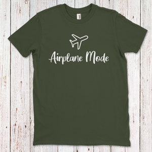 Op de afbeelding: Een donkergroen T-shirt met een wit vliegtuigicoon en de tekst "Airplane Mode" in wit cursief schrift.