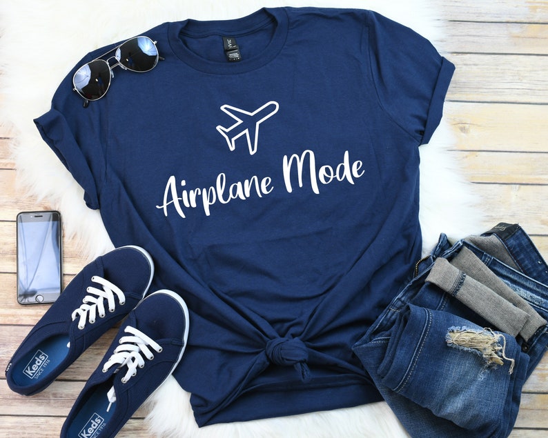 Op de afbeelding: Een marineblauw t-shirt met een witte vliegtuigafbeelding en de tekst "Airplane Mode" in wit.
