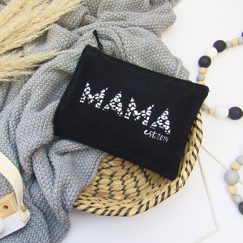 May include: Black canvas zippered pouch with the word "MAMA" in white with a leopard print design and the text "est. 2014" underneath.