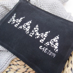 May include: Black canvas zippered pouch with white leopard print lettering that reads "MAMA est. 2014".