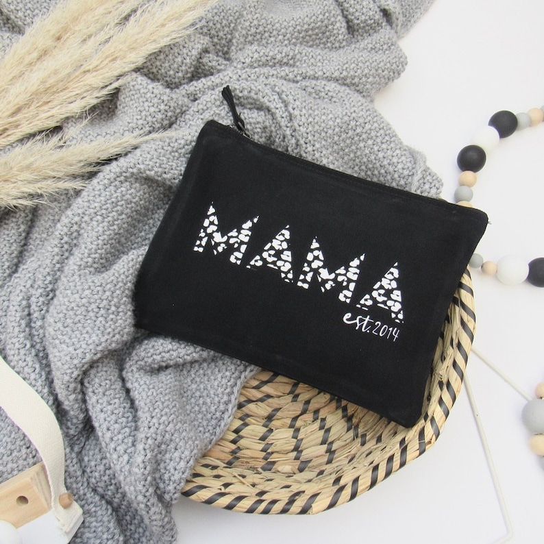 May include: Black zippered pouch with the word "MAMA" in white with a leopard print design. The pouch also has the text "est. 2014" in white.