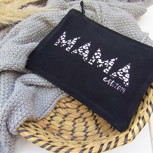 May include: Black canvas zippered pouch with a white geometric design that says "MAMA est. 2014".