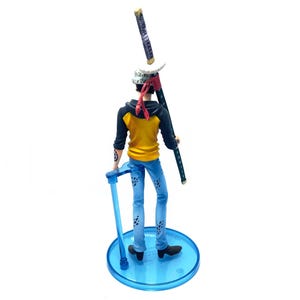Pu&ograve; includere: Statuetta dettagliata di un personaggio della serie anime One Piece. La figura indossa una felpa con cappuccio gialla e nera, jeans blu e una bandana rossa. Tiene una katana e si trova su una base circolare blu.