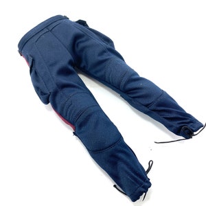 Puede incluir: Un pantal&oacute;n azul oscuro con detalles rojos y rodilleras. El pantal&oacute;n tiene un cord&oacute;n de ajuste en la parte inferior de cada pierna.