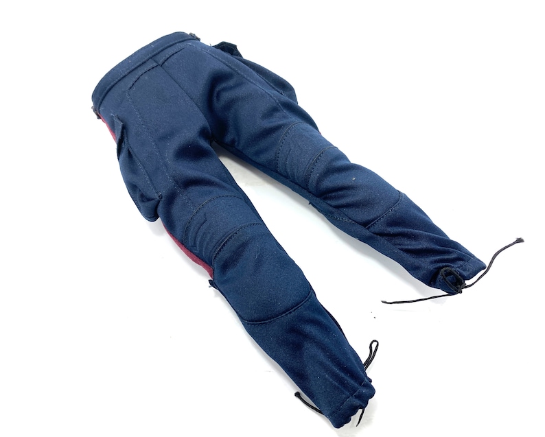 Puede incluir: Un pantal&oacute;n azul oscuro con detalles rojos y rodilleras. El pantal&oacute;n tiene un cord&oacute;n de ajuste en la parte inferior de cada pierna.
