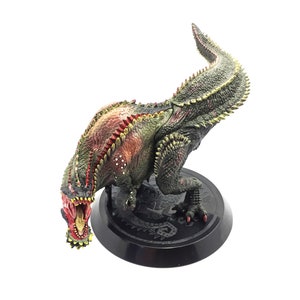May include: A detailed figurine of a dinosaur with a menacing open mouth. The figure is primarily green, red, and yellow, with a textured skin effect. It stands on a black circular base, showcasing intricate details.