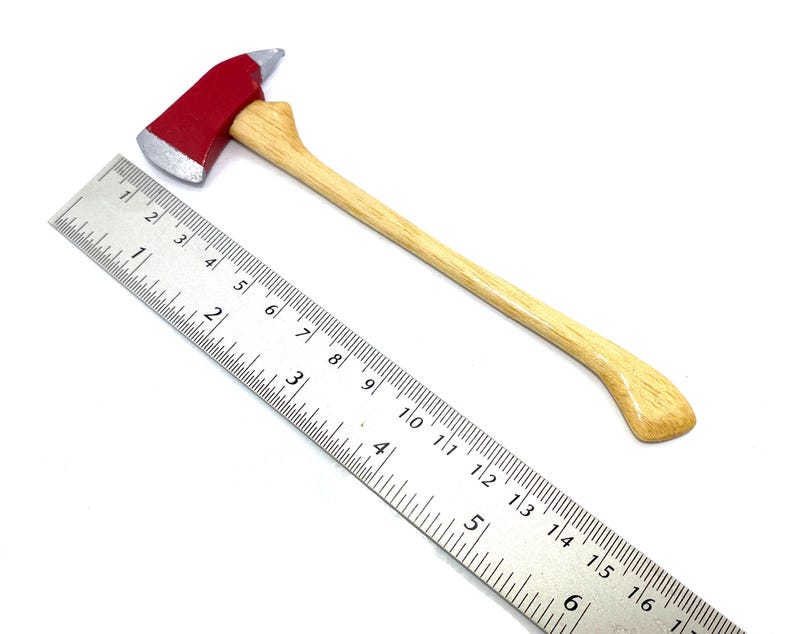 Pode incluir: Um machado de bombeiro de brinquedo vermelho e prateado com cabo de madeira. O machado tem aproximadamente 30 cm de comprimento e est&aacute; ao lado de uma r&eacute;gua para escala.