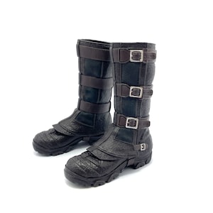 May include: A pair of black leather boots with brown straps and buckles. The boots have a textured surface and a chunky sole.