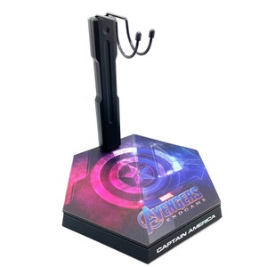K&ouml;nnte beinhalten: Schwarzer Actionfigurenst&auml;nder mit Captain America Endgame-Motiv. Der St&auml;nder hat einen schwarzen Metallarm mit einem Haken und eine Basis mit einer Grafik von Captain Americas Schild und dem Avengers Endgame-Logo.