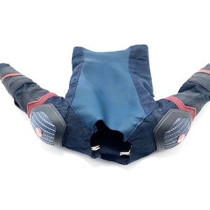 Op de afbeelding: Een zwart en blauw gepolsterd kostuum met rode accenten. Het kostuum heeft lange mouwen en elleboogbeschermers.