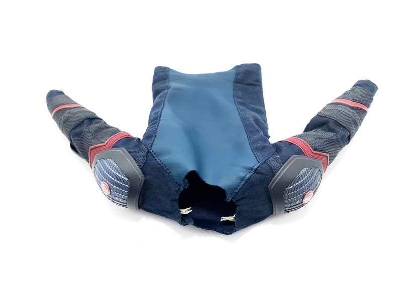 Op de afbeelding: Een zwart en blauw gepolsterd kostuum met rode accenten. Het kostuum heeft lange mouwen en elleboogbeschermers.