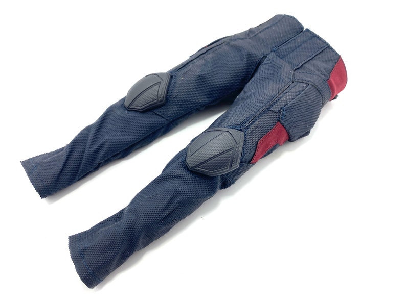 May include: Black trousers with red and black accents. The trousers have knee pads and are made of a textured fabric.