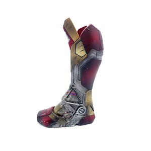 Pu&ograve; includere: Uno stivale di Iron Man metallico rosso, oro e argento, con pannelli intricati e dettagli meccanici. Lo stivale &egrave; un oggetto di scena o da collezione, con un aspetto usurato, che suggerisce danni da battaglia. Il design &egrave; basato sull'iconico supereroe.
