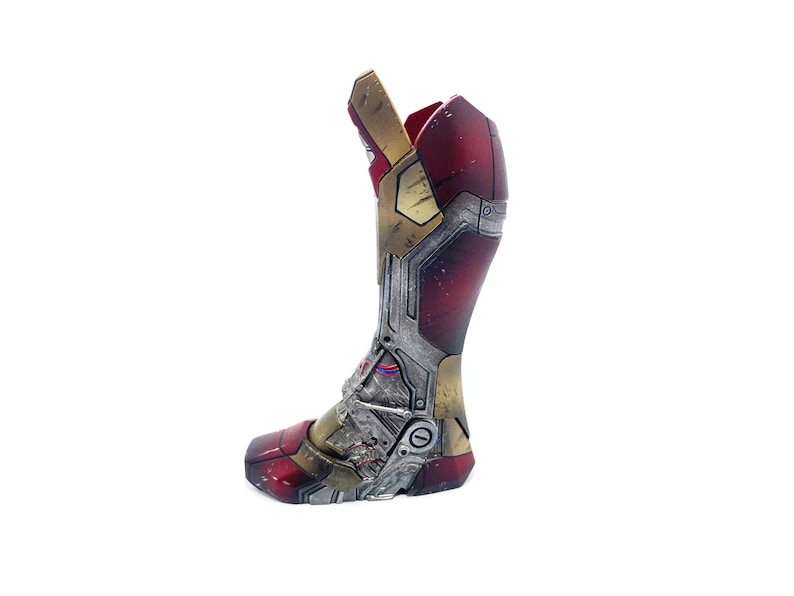 Pu&ograve; includere: Uno stivale di Iron Man metallico rosso, oro e argento, con pannelli intricati e dettagli meccanici. Lo stivale &egrave; un oggetto di scena o da collezione, con un aspetto usurato, che suggerisce danni da battaglia. Il design &egrave; basato sull'iconico supereroe.