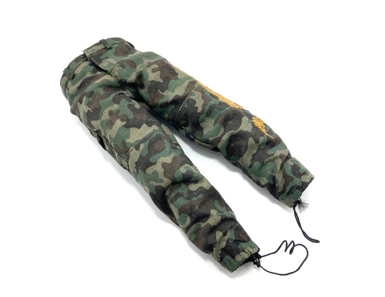May include: Camouflage trousers with a green, brown and black pattern. The trousers have a drawstring at the bottom of the legs.