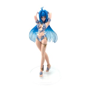 May include: A figurine of a woman with long blue hair and a silver outfit. The figure is standing on a clear base, with her arms raised. The outfit includes a bikini top, shorts, and armbands. She is wearing high heels.