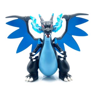 May include: A black and blue dragon figurine with large blue wings and accents. The dragon has a light blue belly and a fierce expression. The figurine is standing on a white surface.