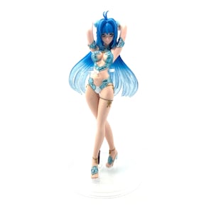 May include: A figurine of a woman with long, flowing blue hair and a matching bikini. The figure is posed with arms raised, wearing sandals and decorative armbands. The figure is on a clear stand against a white background.