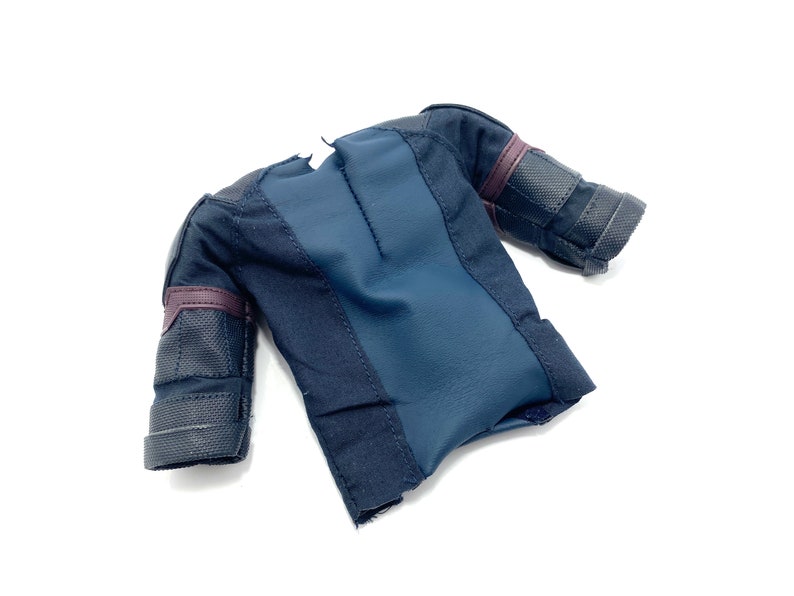 Puede incluir: Una camisa de manga corta de color azul oscuro y negro con una tela texturizada. La camisa tiene una cremallera en la espalda y un ribete negro y morado en las mangas.