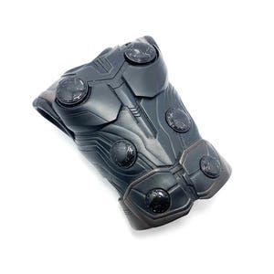 May include: Black plastic costume chest piece with a textured surface and multiple circular details.